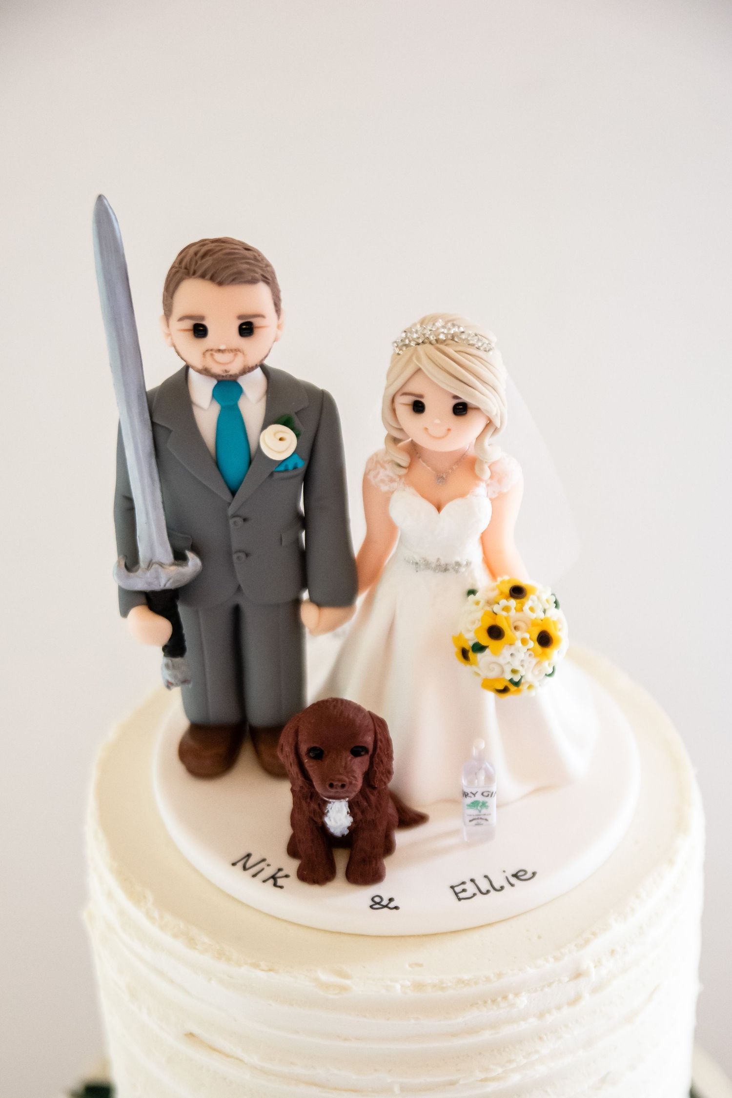 Custom wedding cake topper featuring bride and groom figurines with a small brown dog.