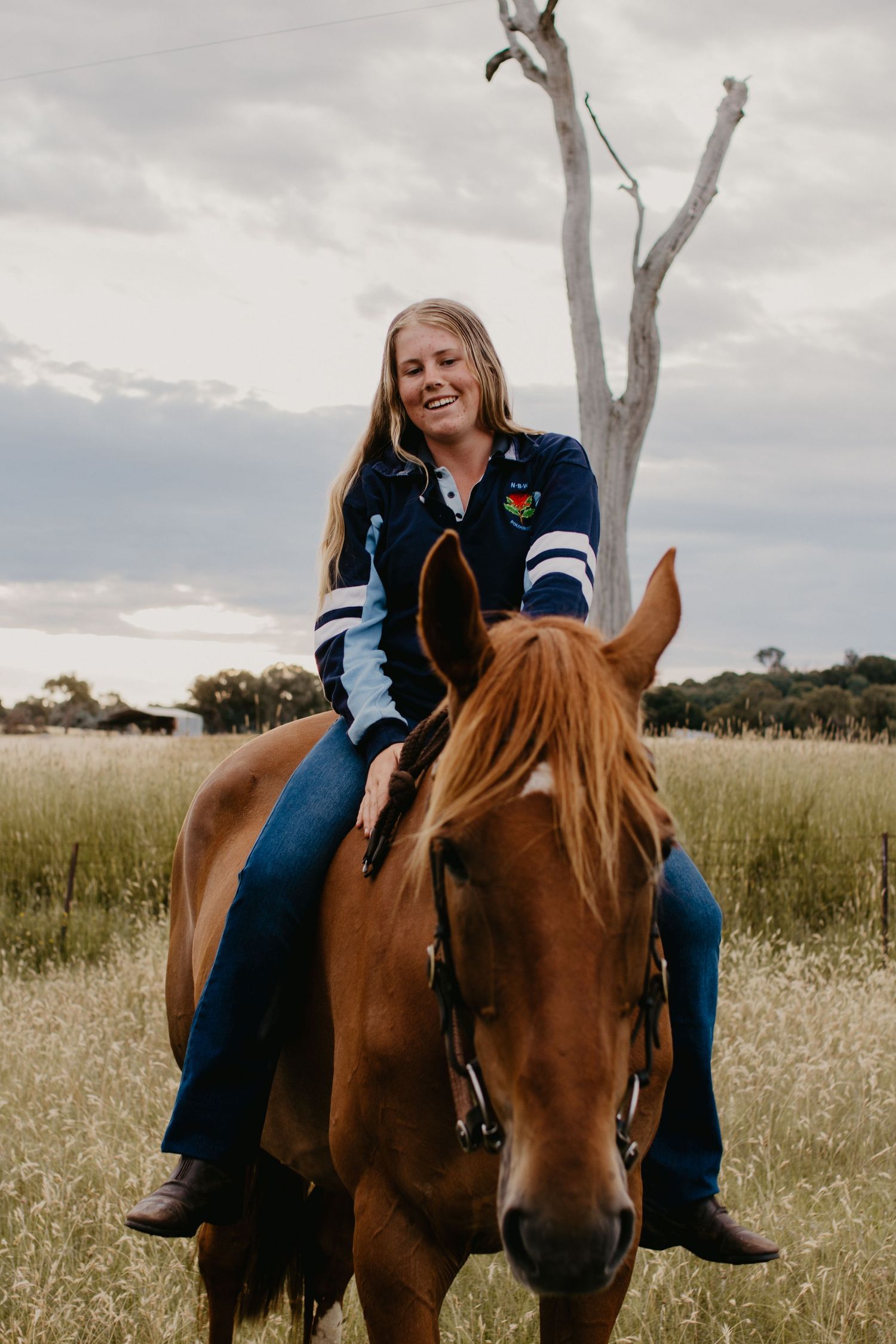 Girl on her horse bareback standing in the paddock with a shed in the background.