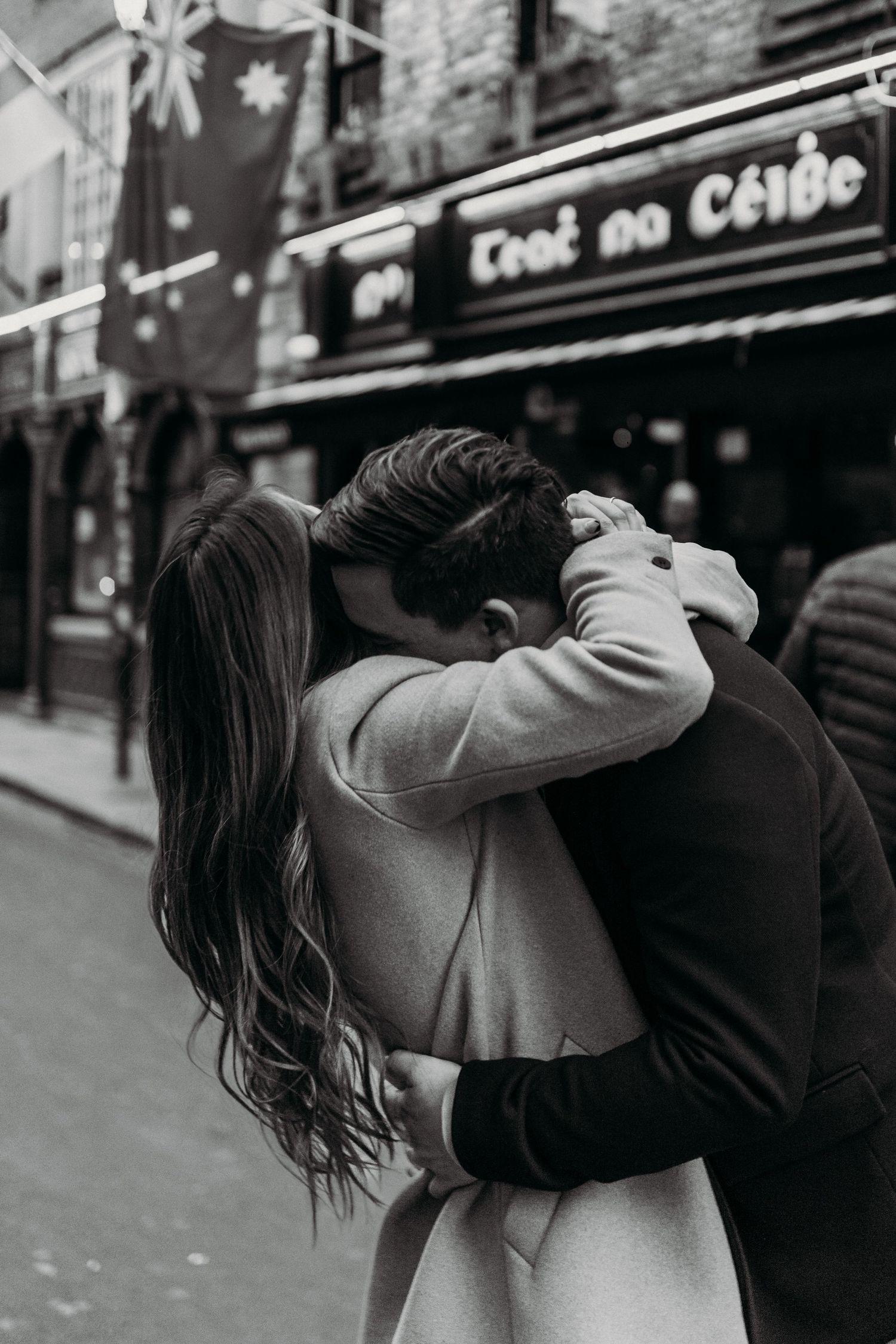 Intimate black and white photo of a couple embracing outside Tigh na Ceili pub.