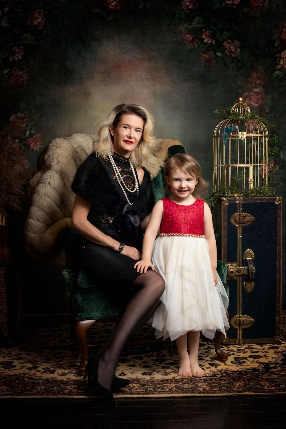 Elegant studio portrait with vintage birdcage and pearls featuring black and red formal attire.