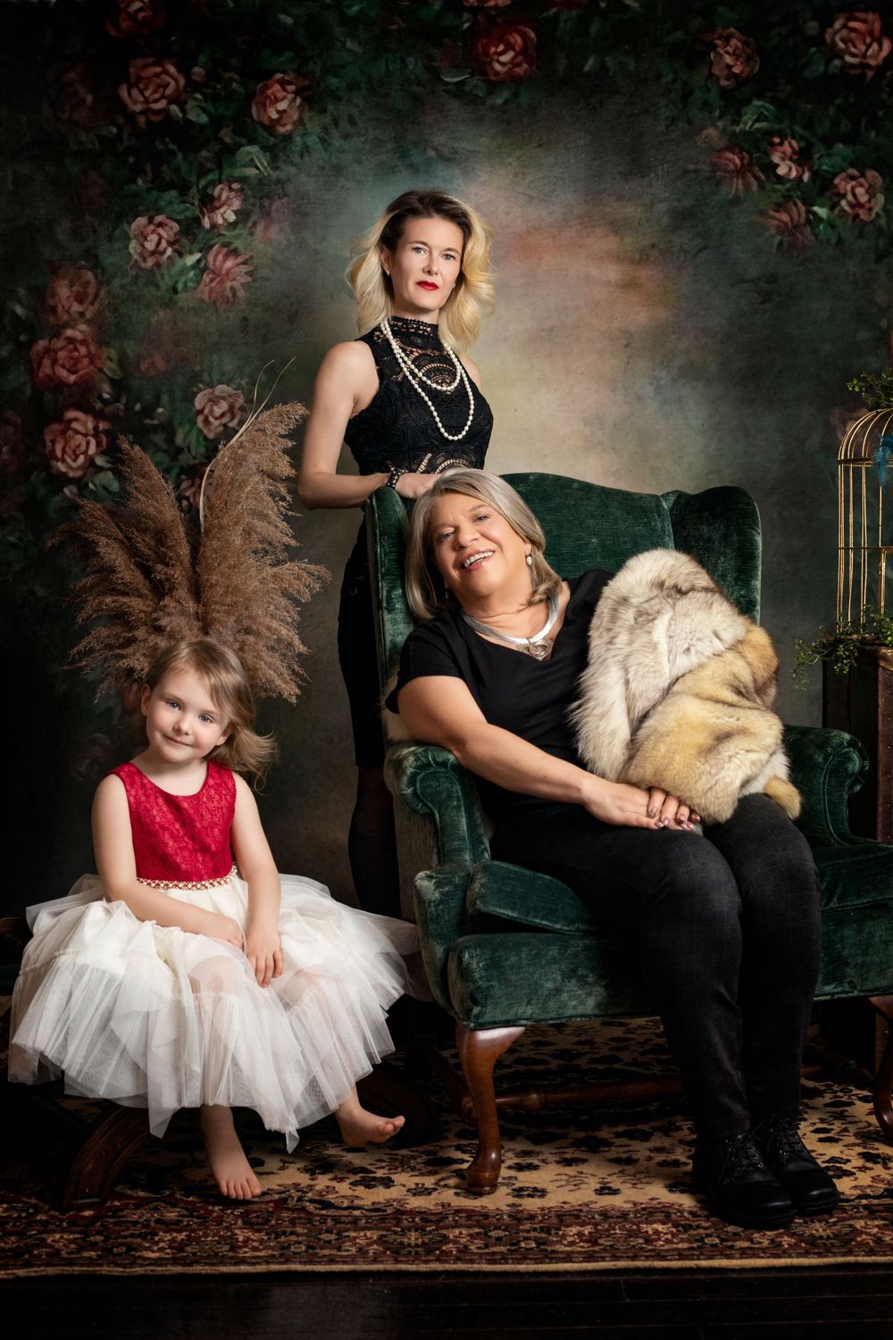 Studio portrait with vintage furniture and birdcage featuring formal black and red attire.