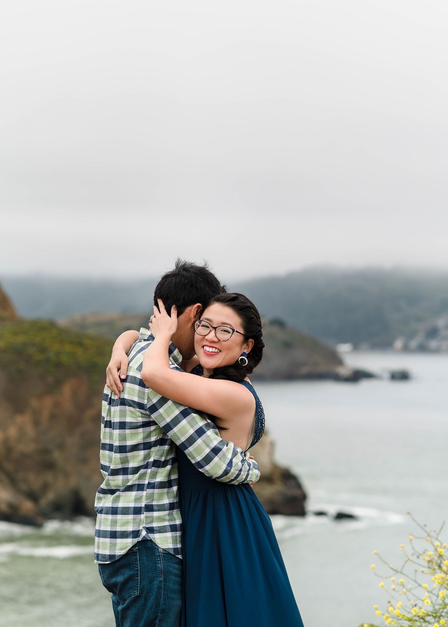 A joyful embrace on a scenic cliff overlooking the Pacific coast.