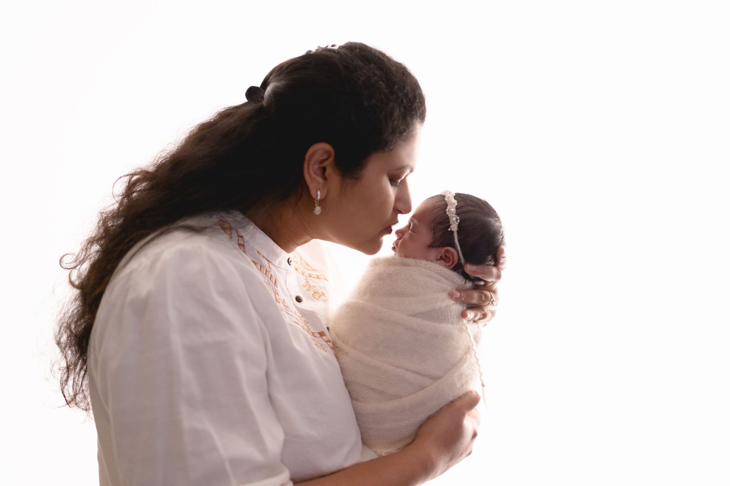 Parents lovingly cradle and bond with their newborn baby in a heartwarming series of artistic silhouettes against white.