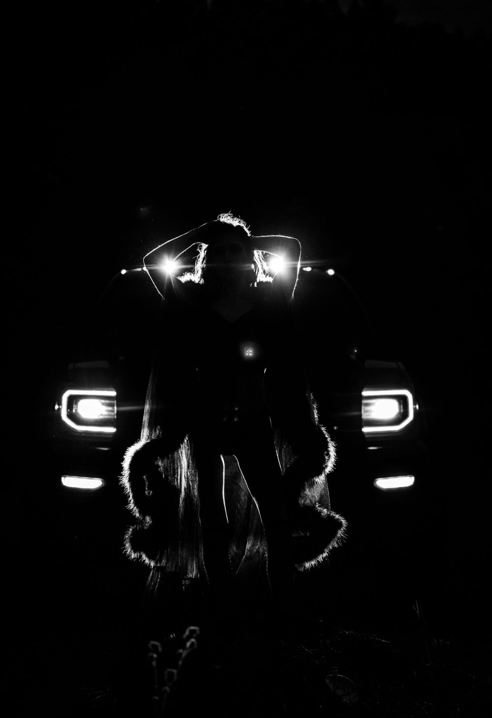 Artistic nighttime photo with silhouettes against car headlights.