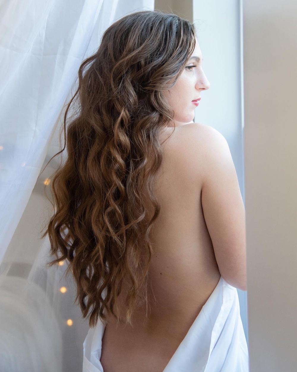 Side profile shot against white curtains with soft natural lighting.