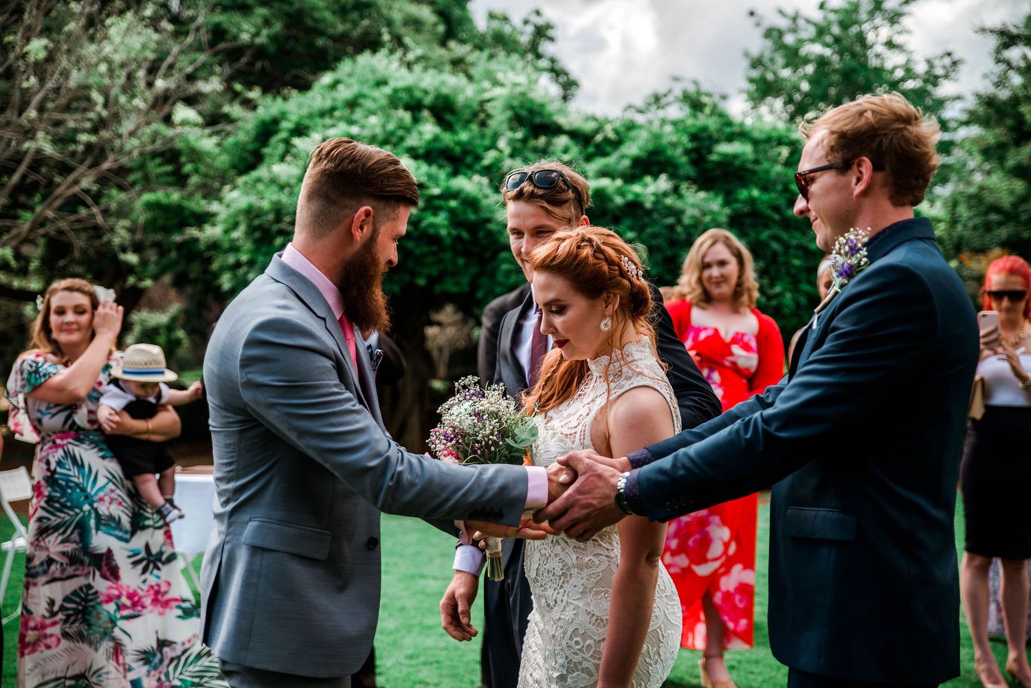 Wedding ceremony moment with couple and officiant in garden setting.