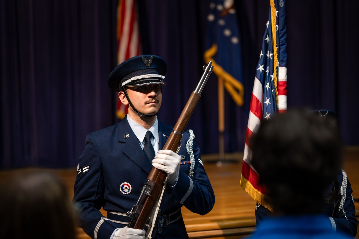 A uniformed honor guard member holding a ceremonial rifle during a military event.