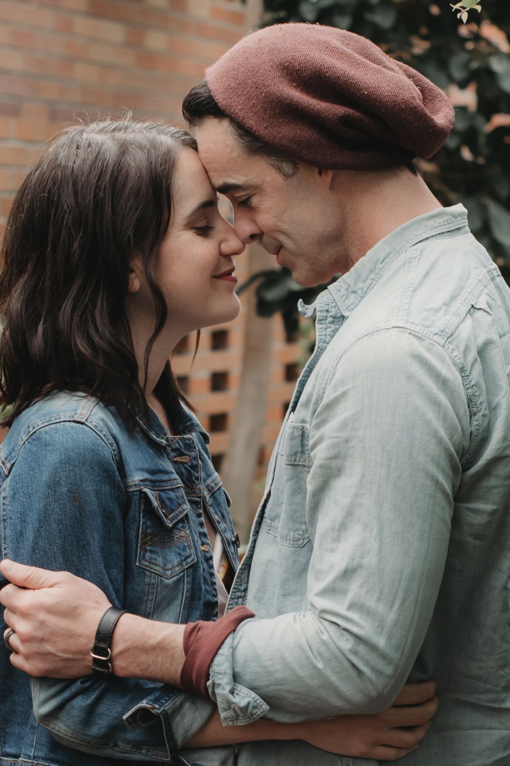A tender romantic moment shared against a brick wall background.