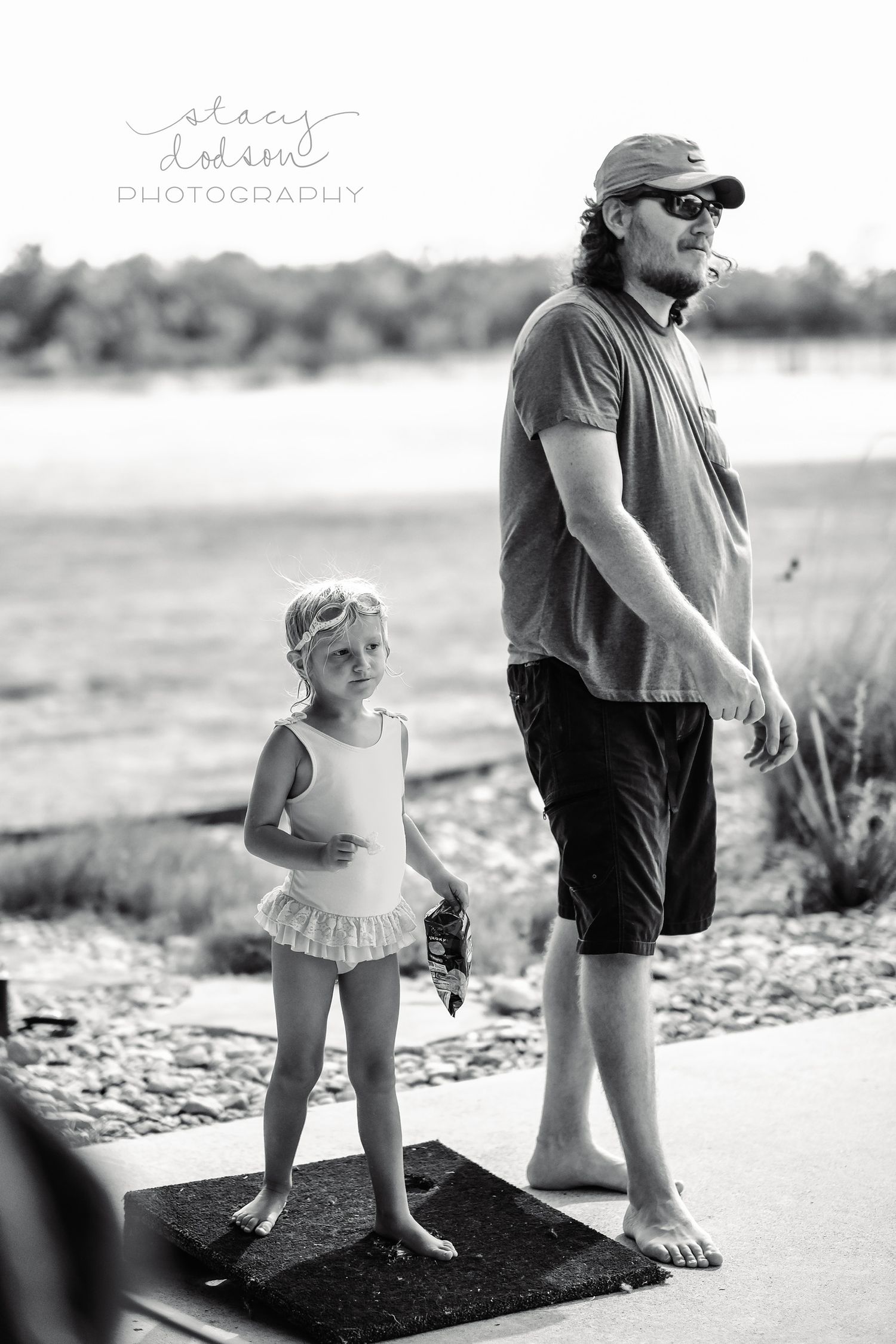 Black and white image of a little girl in a swimsuit standing next to a man playing washers.