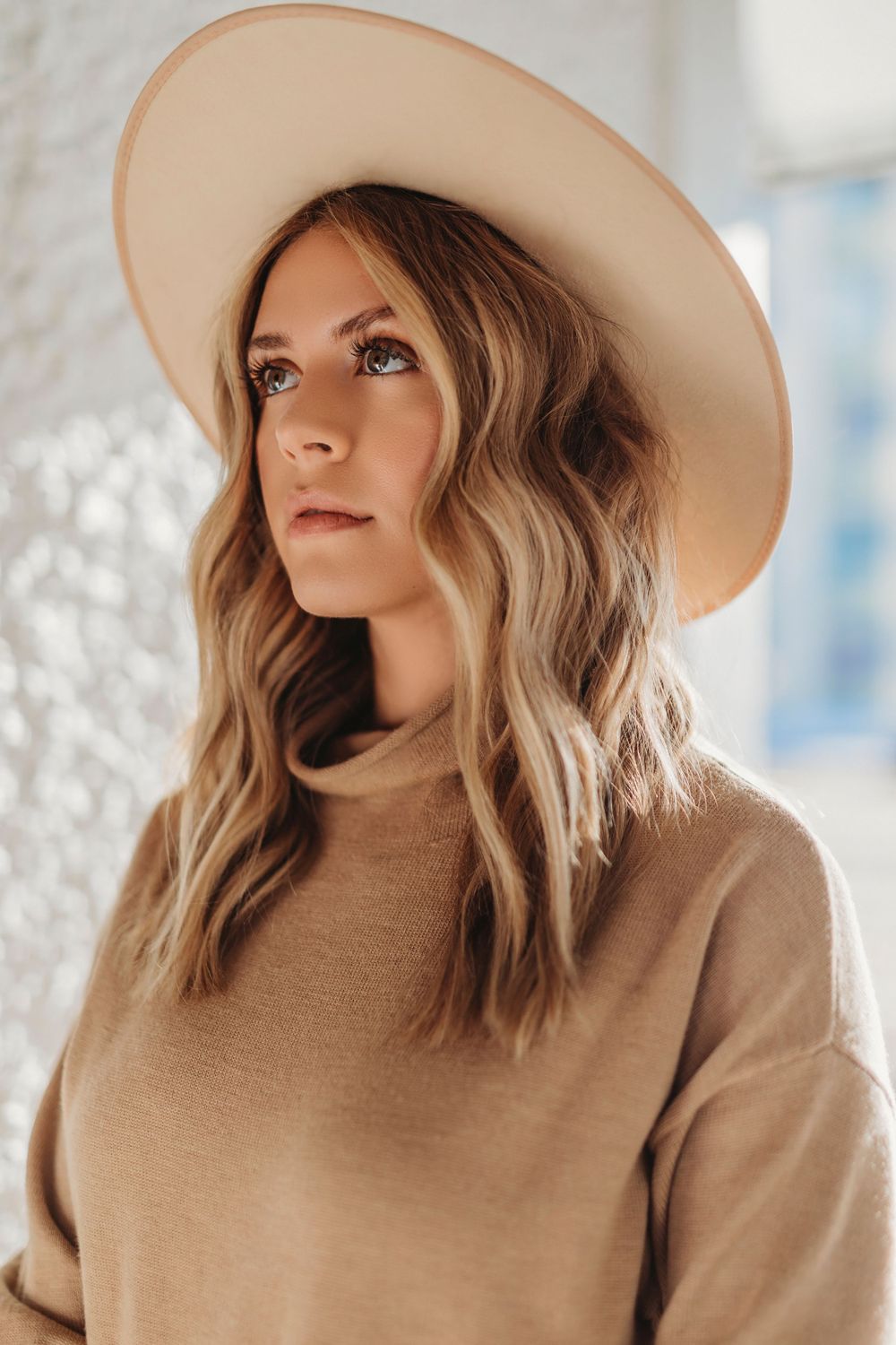 Fashion portrait in neutral tones featuring tan hat and sweater.