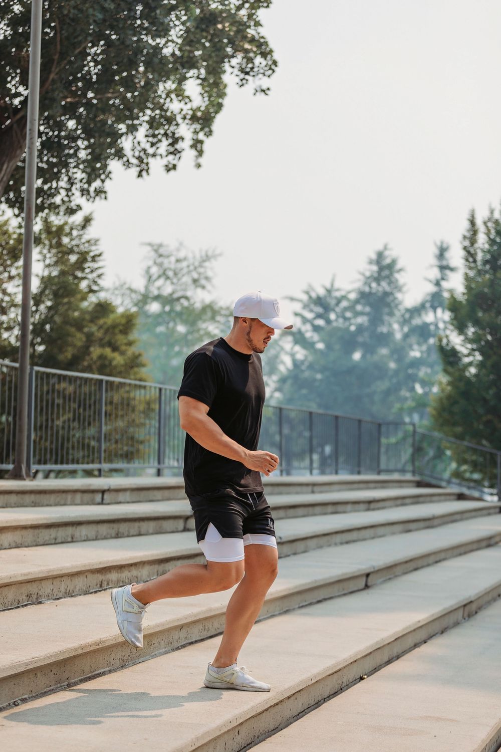 Athletic person jogging down concrete steps in athletic wear and baseball cap.