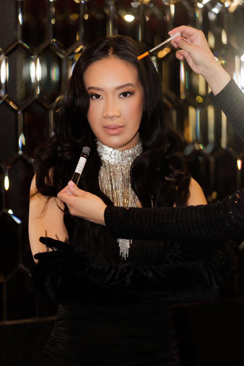 Elegant portrait in black dress with silver necklace against mirrored background.