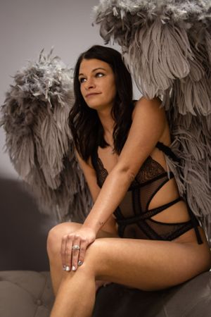 Intimate portrait of model in black lingerie with large feathered wings.