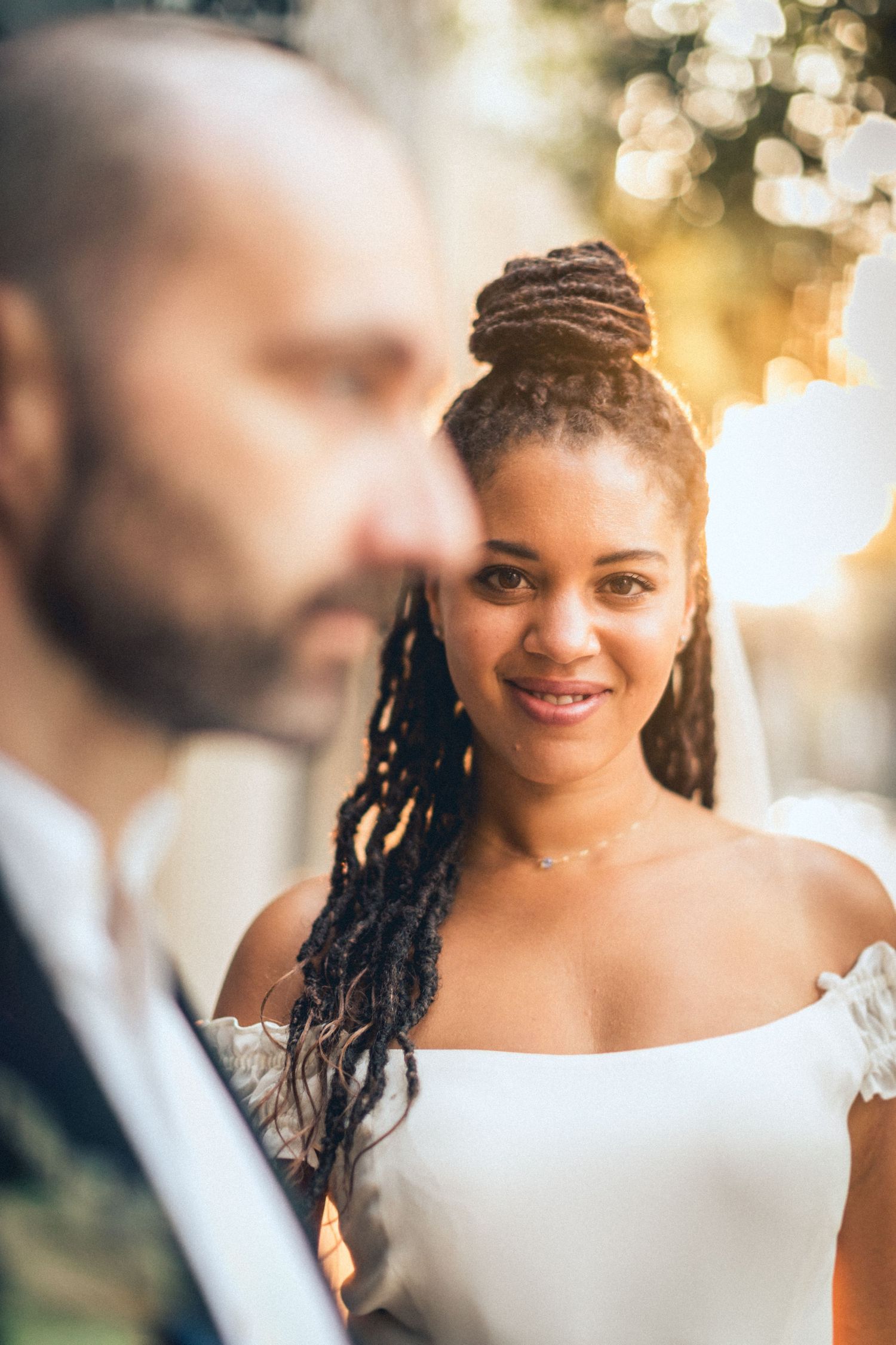 A close-up wedding portrait of a couple with warm bokeh lighting in the background.