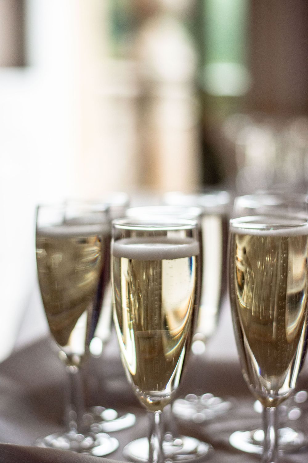 Row of champagne flutes filled with sparkling wine in soft focus.