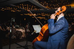 Musician in blue suit playing cello on stage at elegant evening event.