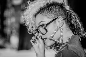 Black and white portrait of woman with curly hair and glasses looking down.