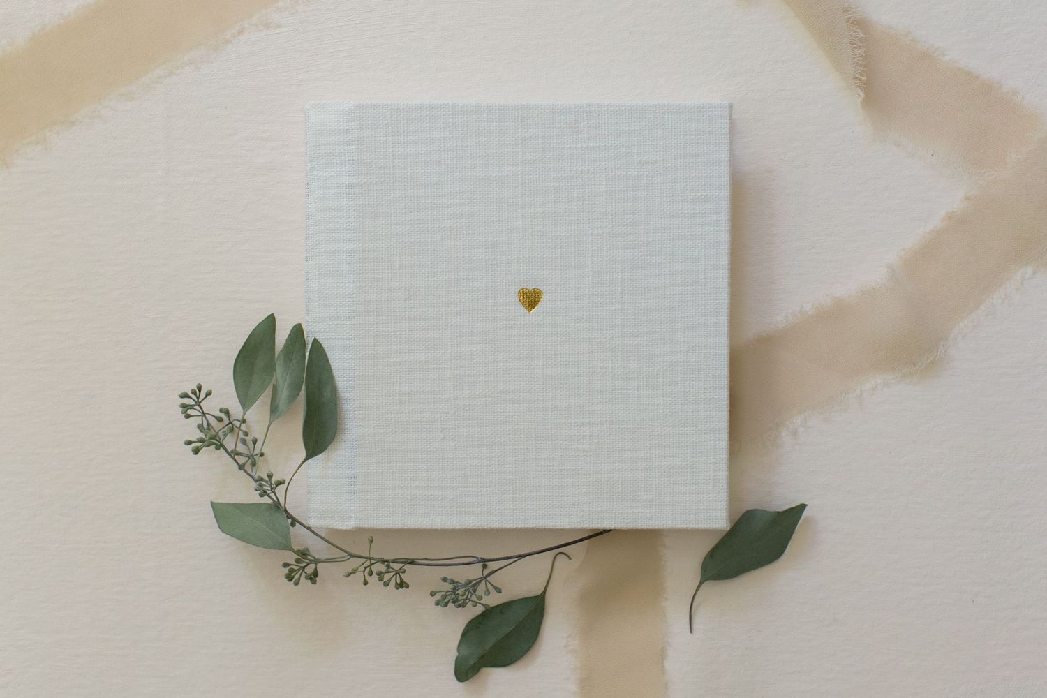 Color swatch samples fanned out with green leaves and white paper on a beige surface.