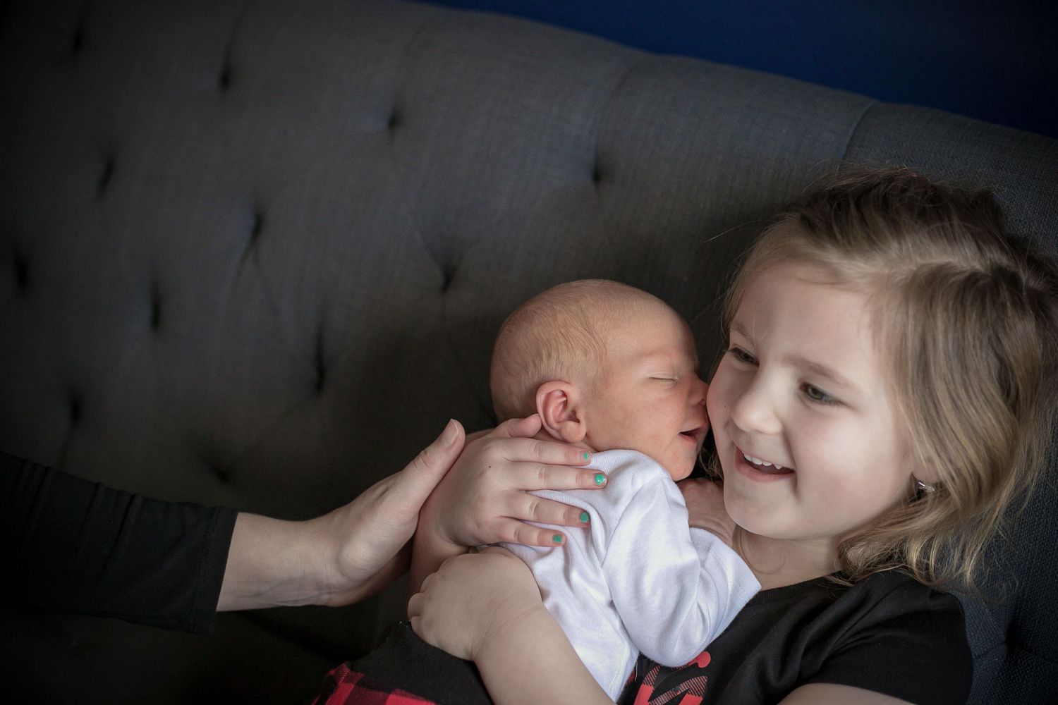 Big sister giggling as her new baby brother gives her "kisses" during their fresh 48 session in Sioux City, IA.
