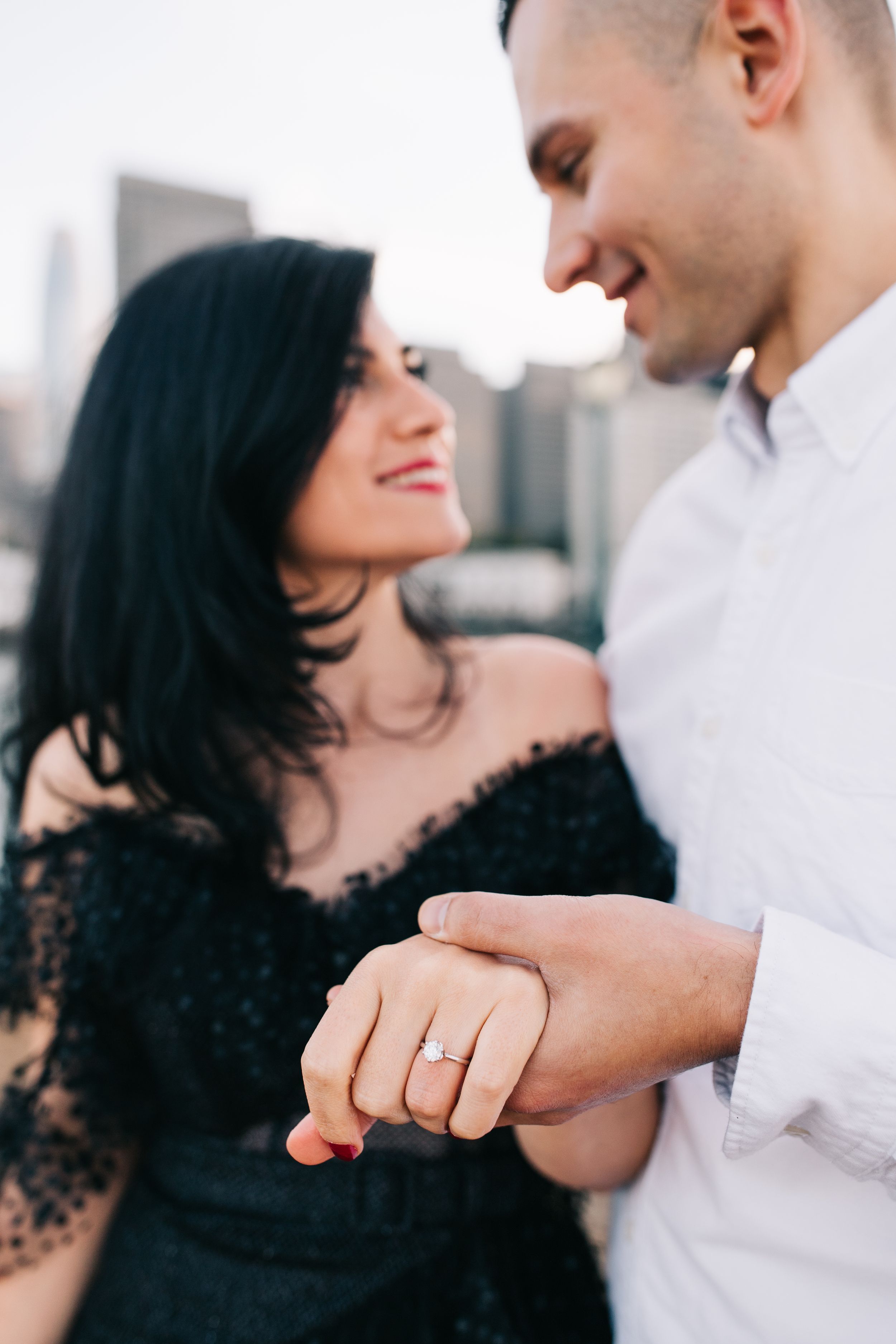 A close-up shot showing an engagement ring as a couple shares a romantic moment in the city.