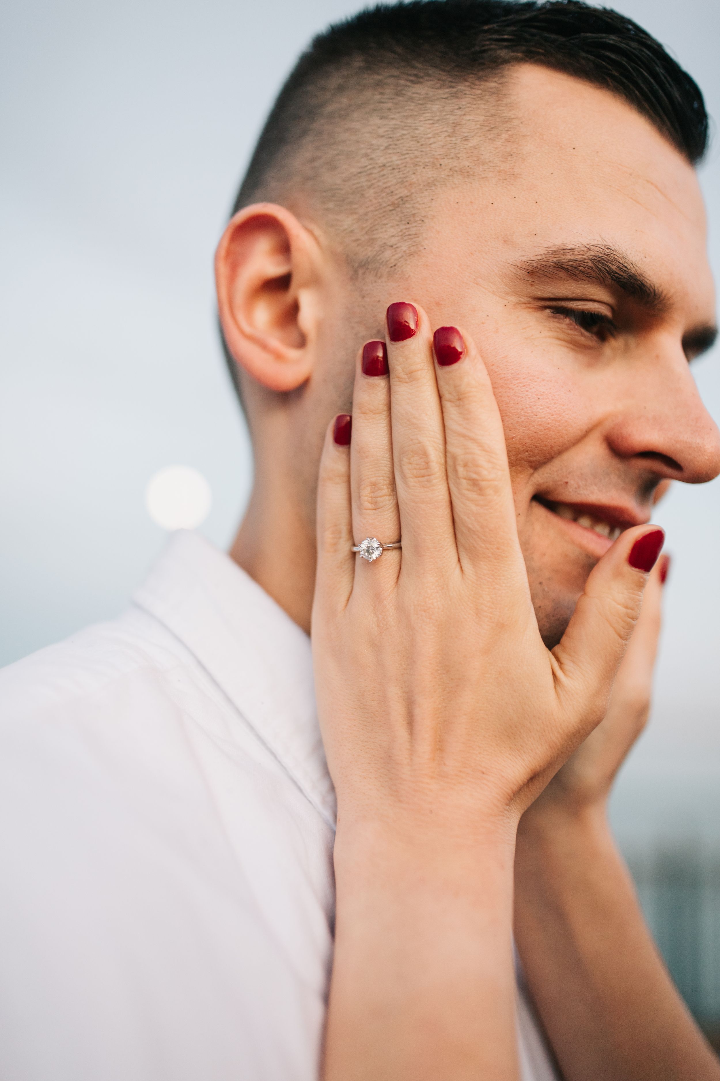 Close-up of engagement ring on hand with red nail polish.