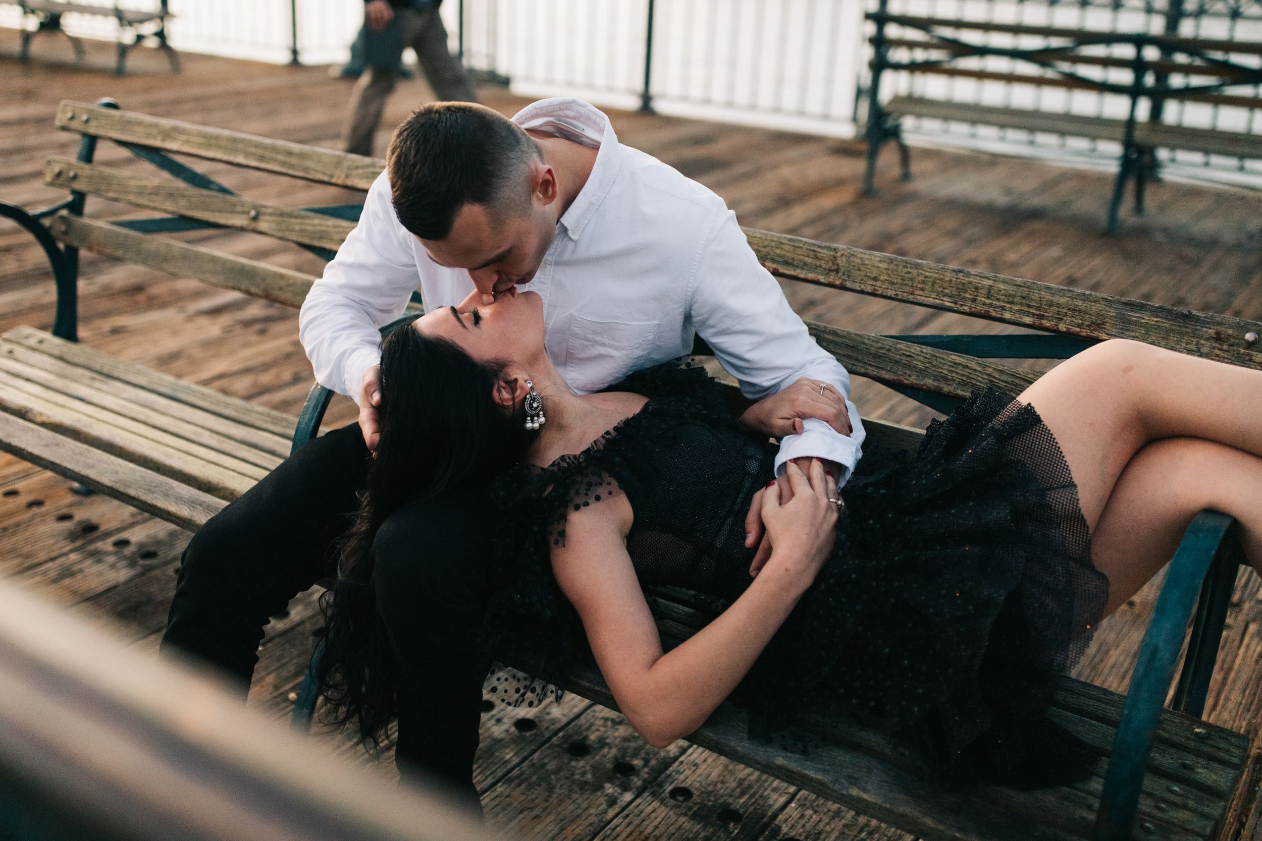 Intimate moment shared on pier bench with urban waterfront backdrop.