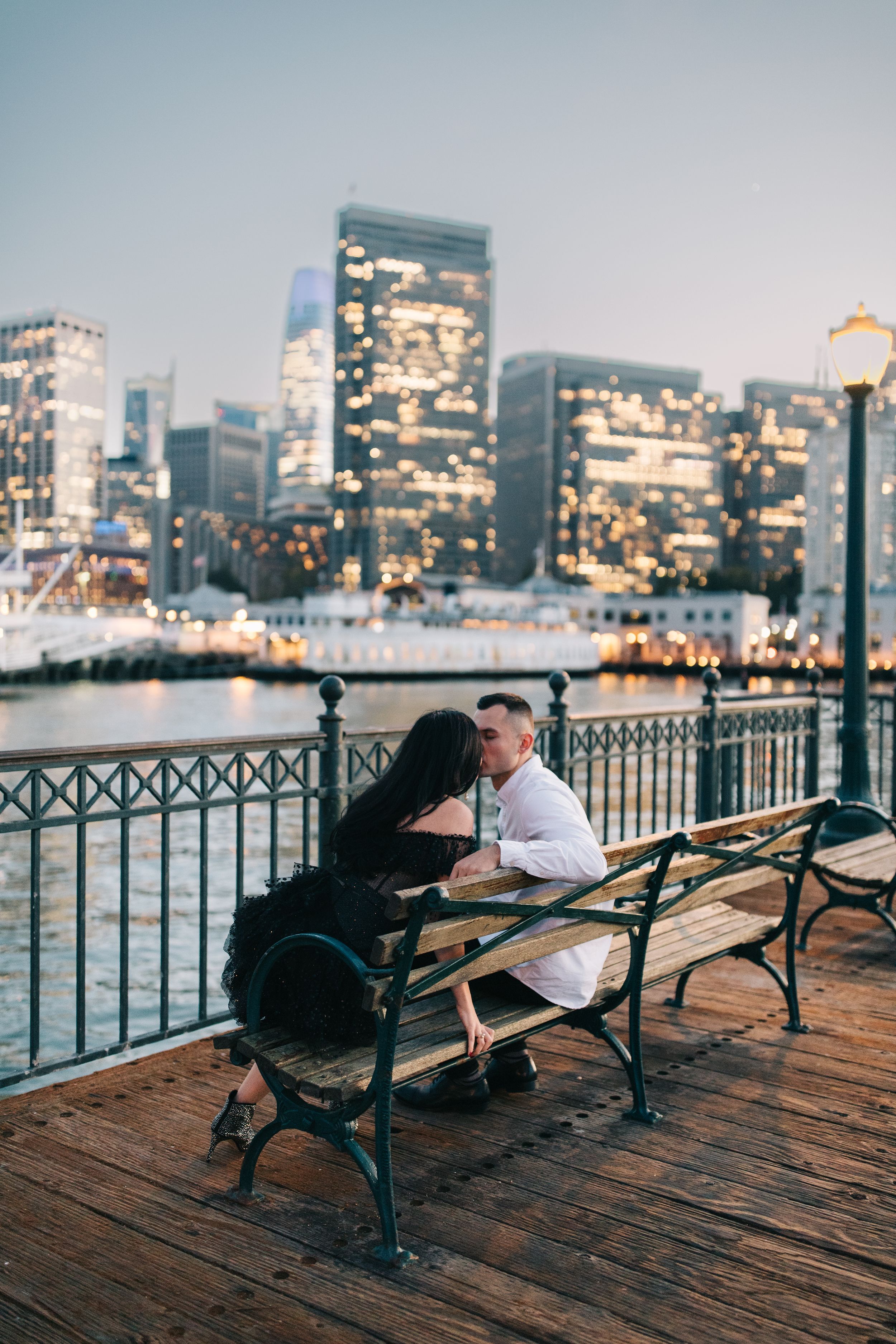 Romantic evening on waterfront pier with illuminated city skyline and glowing streetlamp in San Francisco.