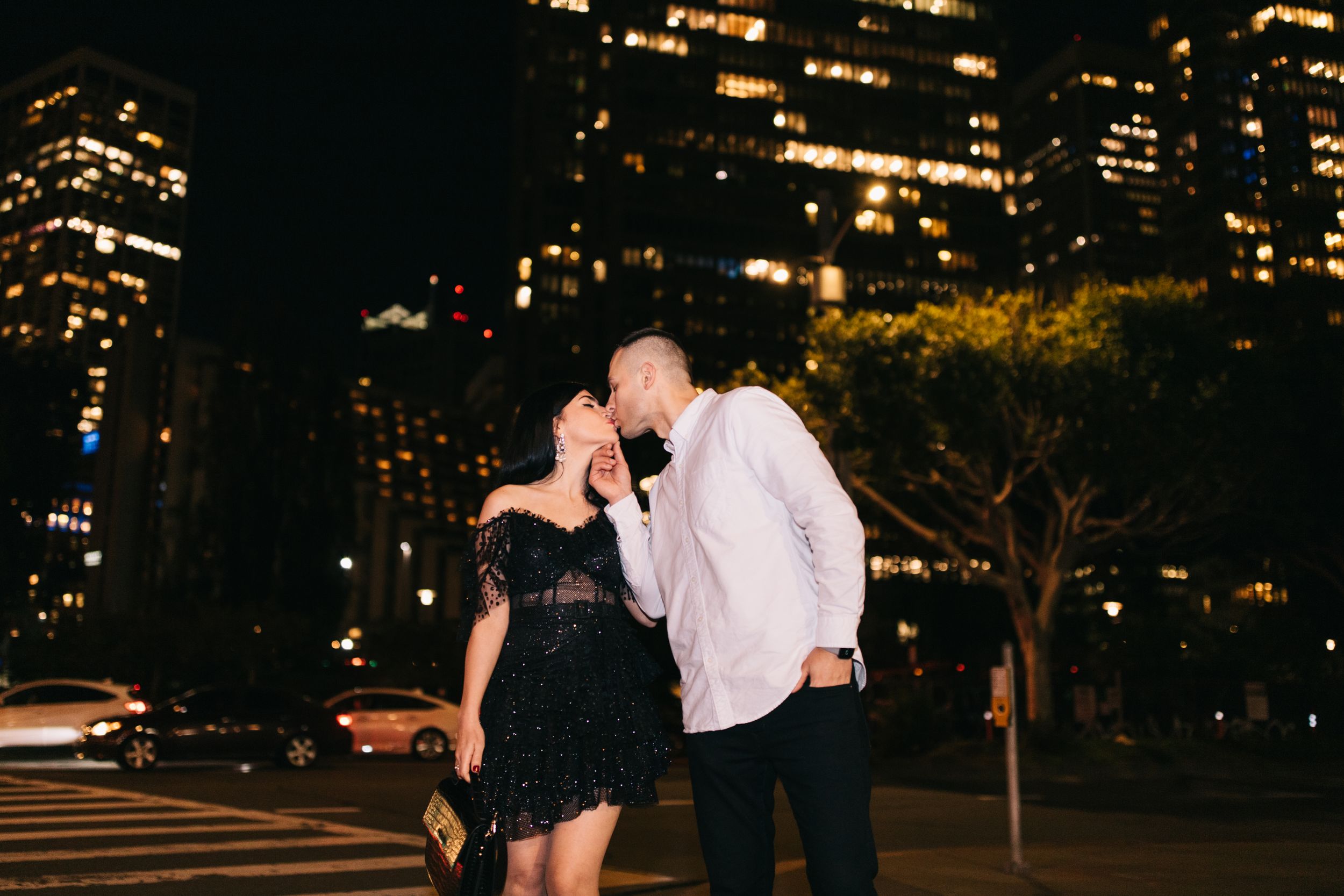 Romantic nighttime portrait with illuminated skyscrapers creating magical urban backdrop.