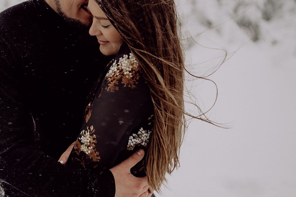 Close-up shot of an embracing couple with long flowing hair against a snowy backdrop.