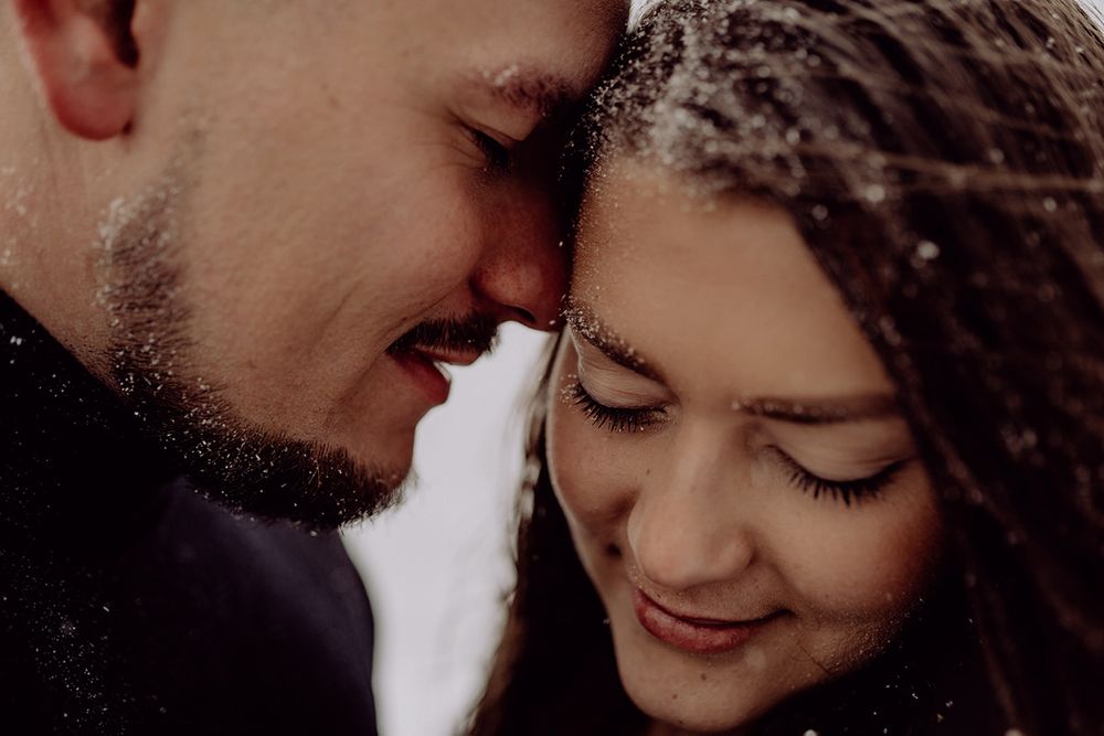 An intimate close-up of a couple sharing a tender forehead touch moment in winter.