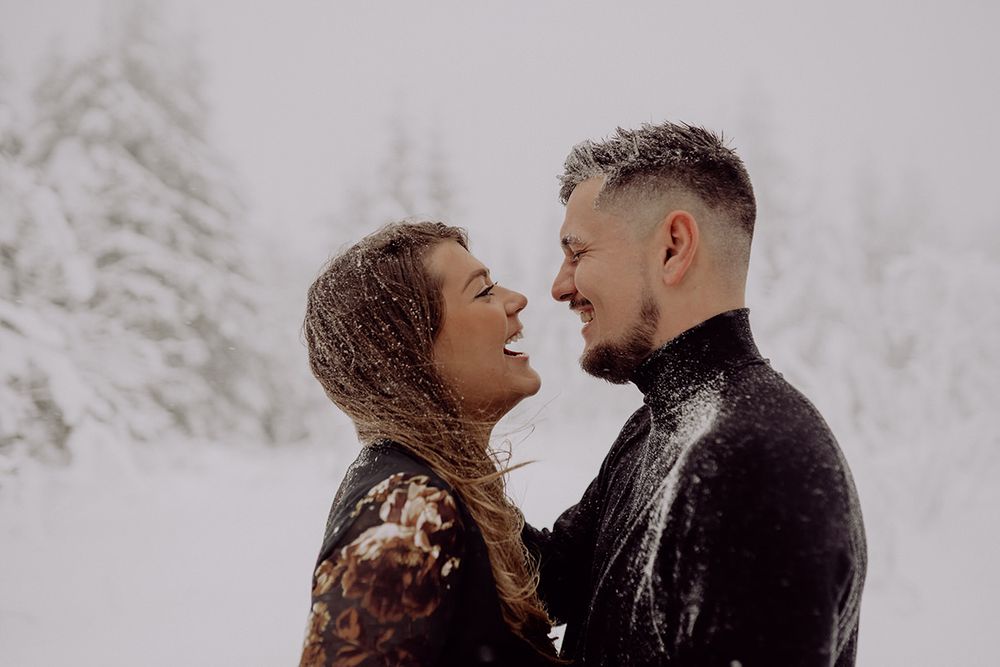A romantic couple shares an intimate moment in a snowy winter forest setting.