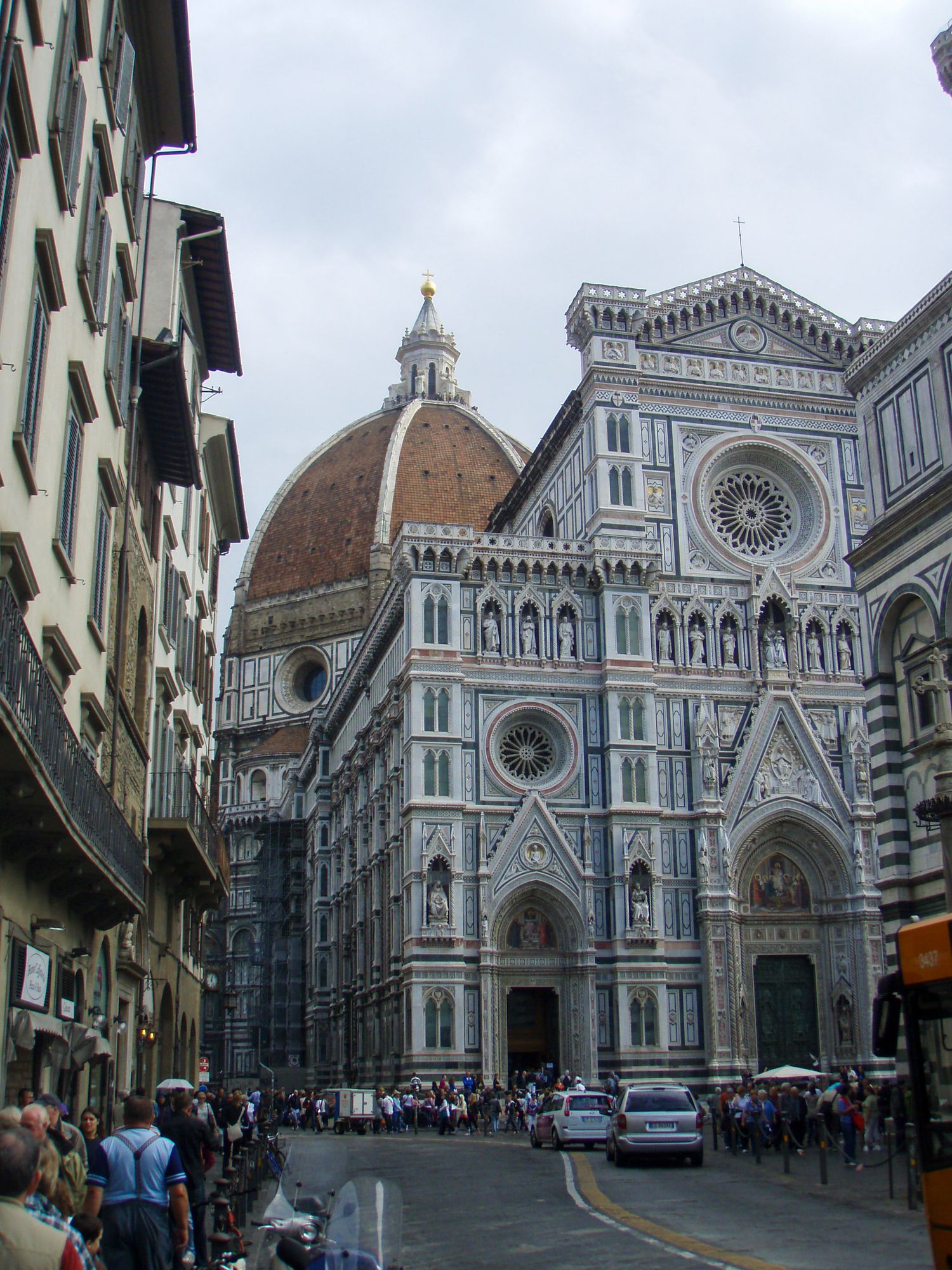 View of Florence Cathedral's iconic Duomo dome and marble facade with tourists gathering in front of the historic church.
