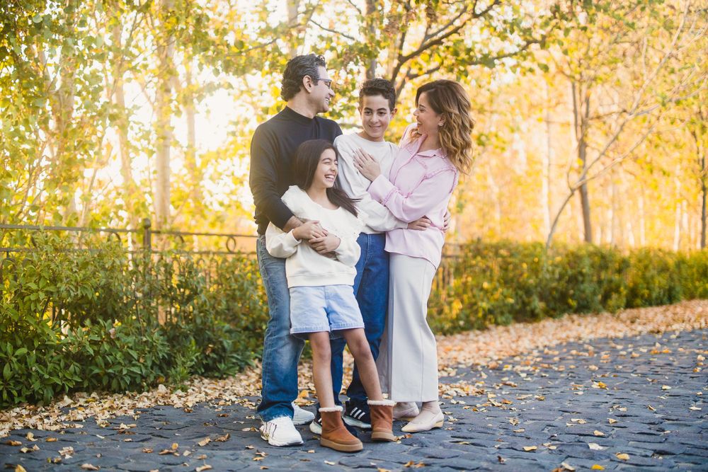 A family shares a tender moment together on a path surrounded by golden autumn foliage.