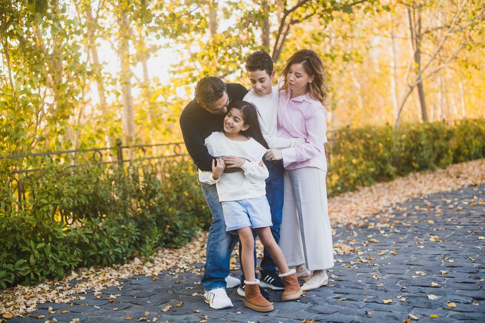 Intimate family moment captured on stone walkway with fall foliage backdrop.