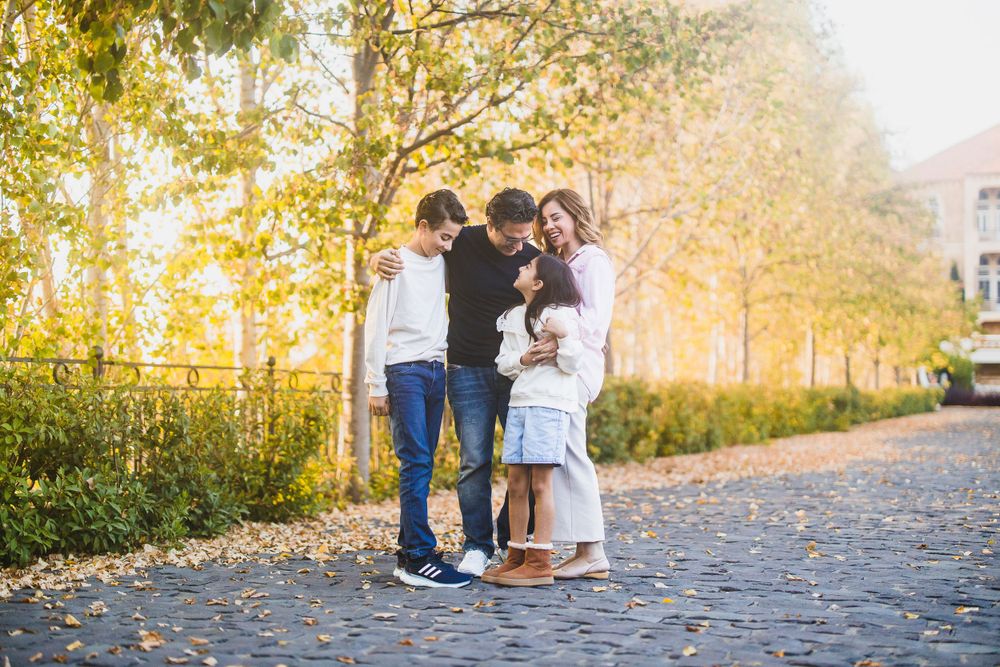 Group sharing a close moment on autumn path with golden trees in background.