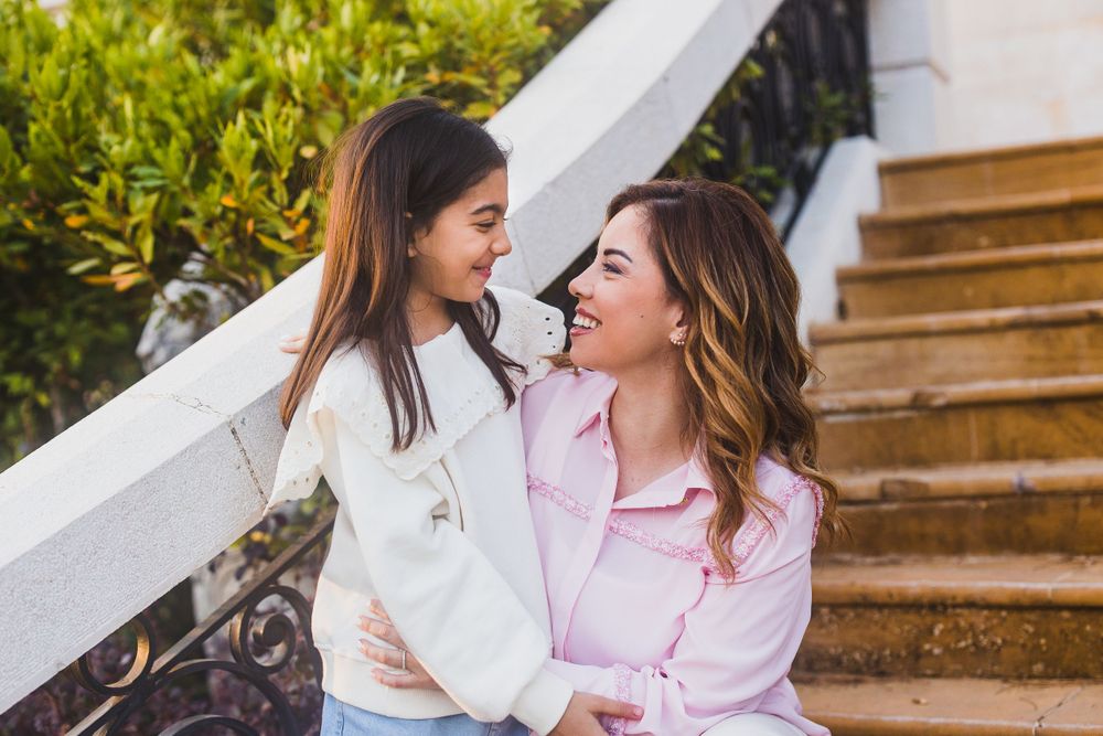 Two people share a joyful moment while sitting on outdoor stairs.