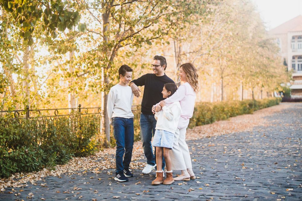 Candid group moment captured on stone path with fall trees and warm lighting.