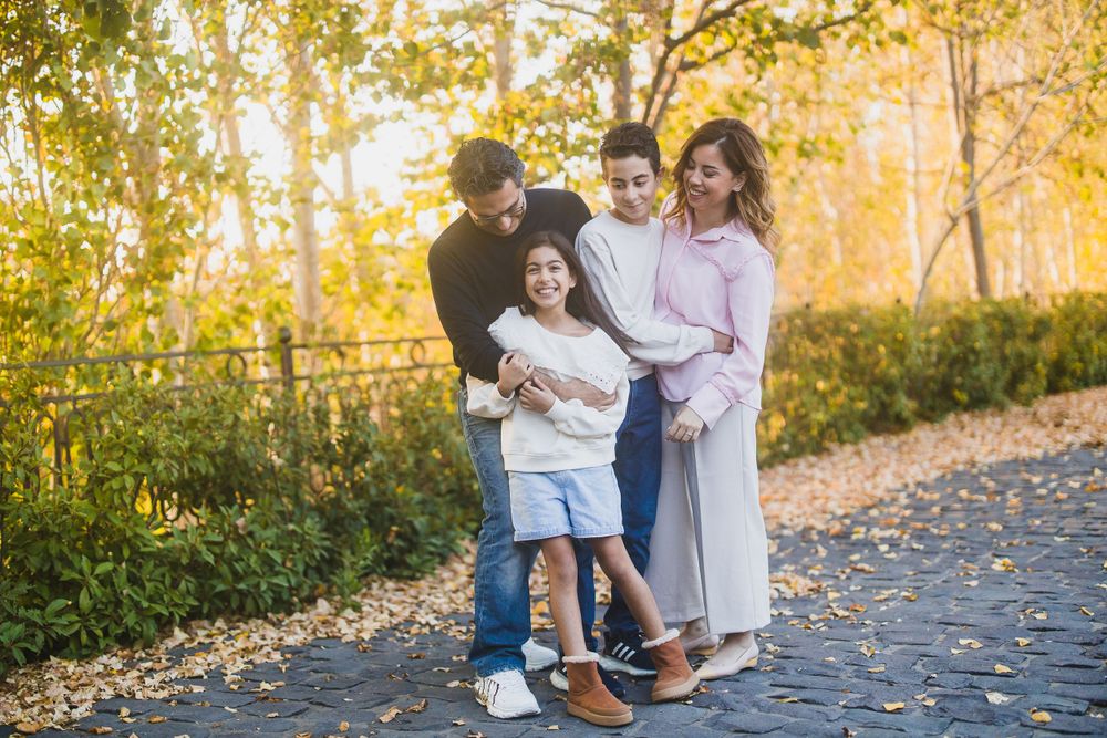 Group standing together on autumn path with golden trees and warm lighting.
