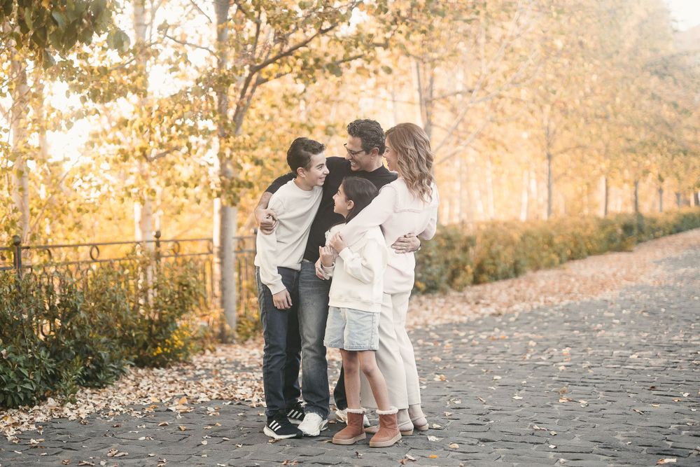 Family sharing an intimate moment together on a fall pathway with warm golden lighting.