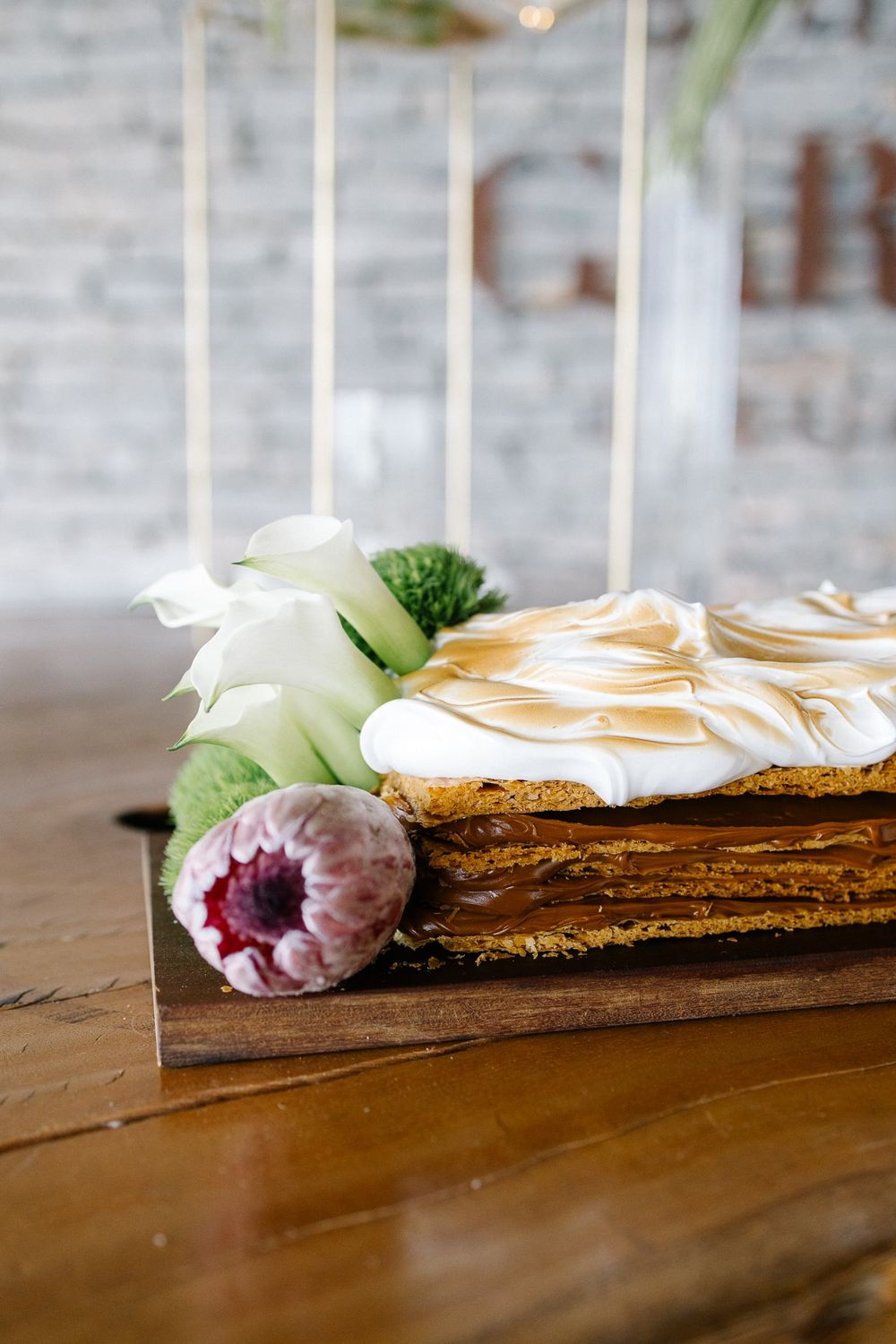 Close-up of a layered dessert with meringue topping and floral decoration.
