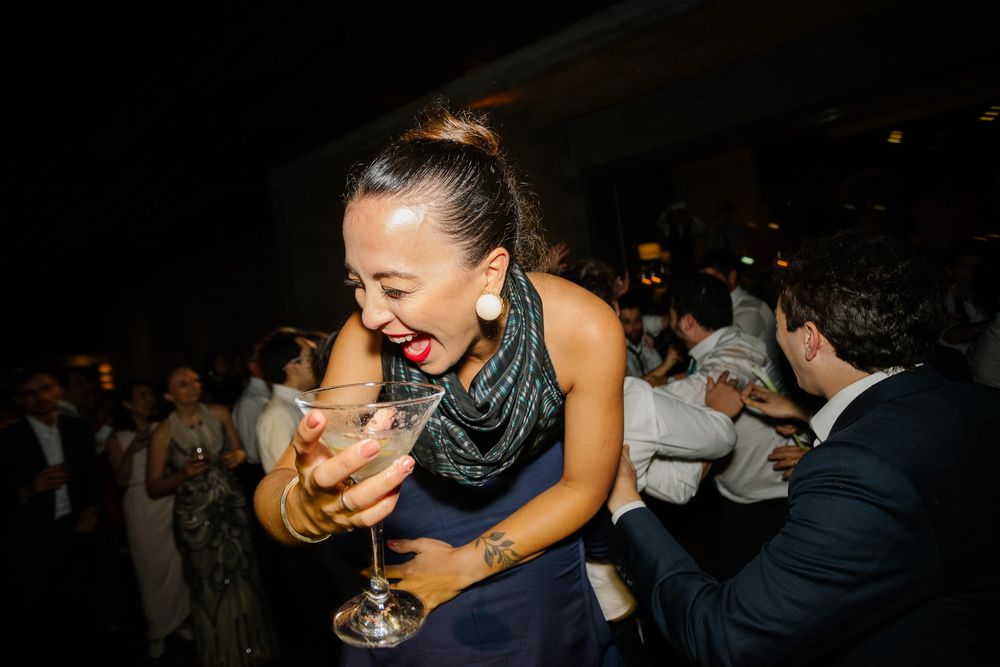 Woman laughing while holding a cocktail glass at a nighttime party celebration.