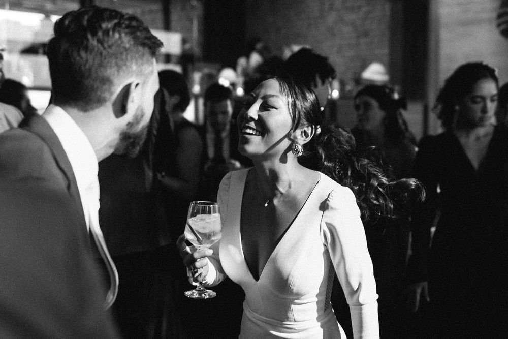 Elegant wedding celebration in black and white showing joyful laughter and champagne.