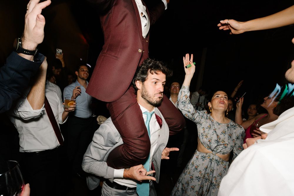 Wedding guests dancing enthusiastically on a dark dance floor.