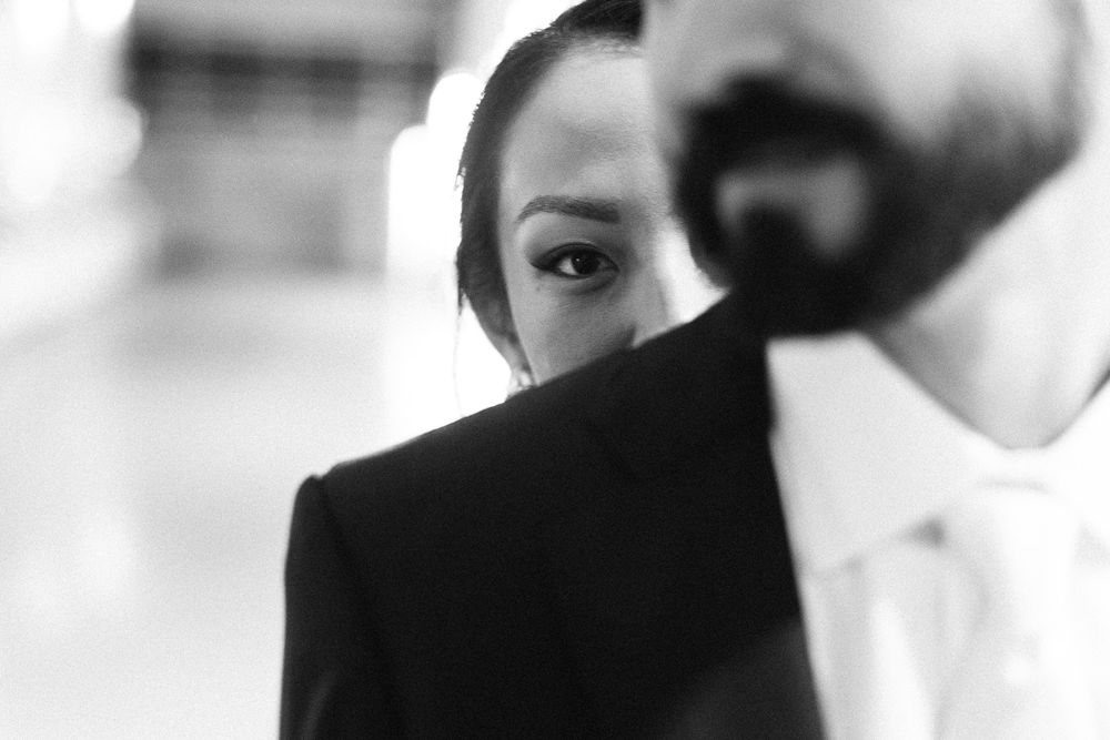 Artistic black and white close-up portrait showing half of a face behind a dark object.