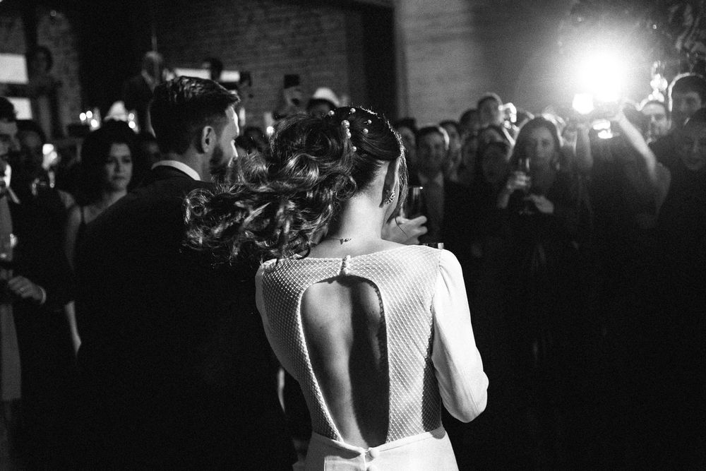 Black and white photo of a wedding reception with a backless dress and photographers capturing the moment.