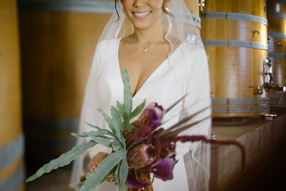 Simple tropical bouquet with pineapple top and purple orchids against wooden wine barrels.