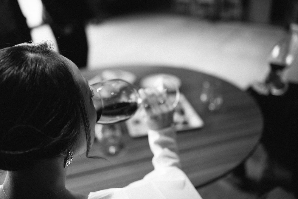 Black and white photo of wine glasses on a table during a wedding reception.