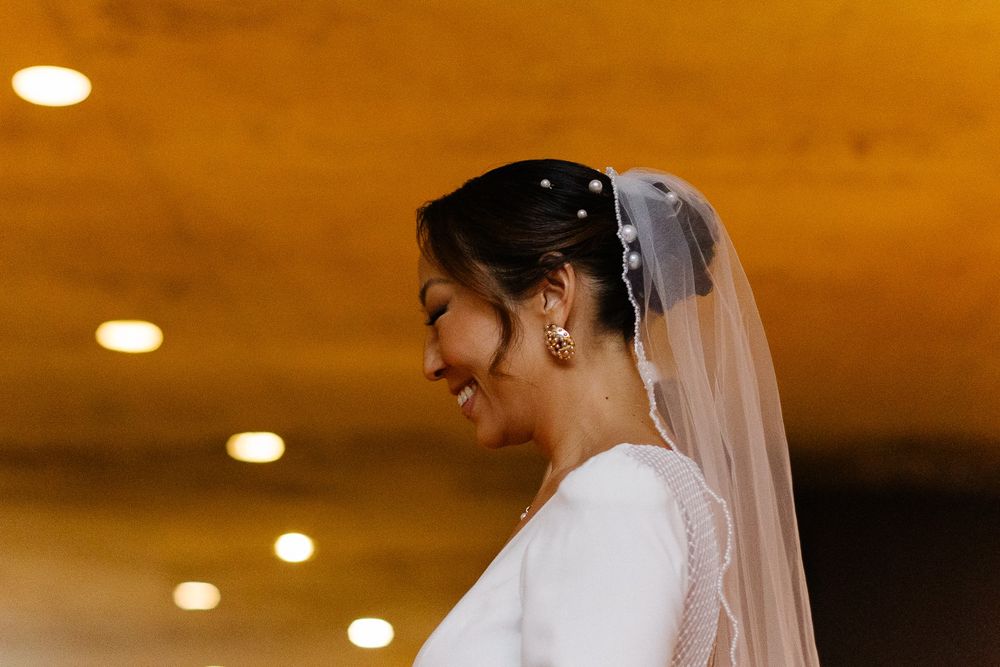 Side profile shot of bride in elegant long-sleeved wedding gown and veil.