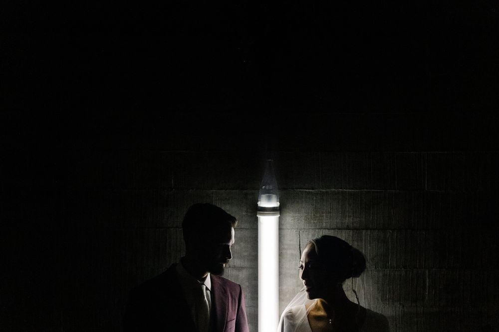 Dramatic silhouette of a couple against a dark wall with a single light source.