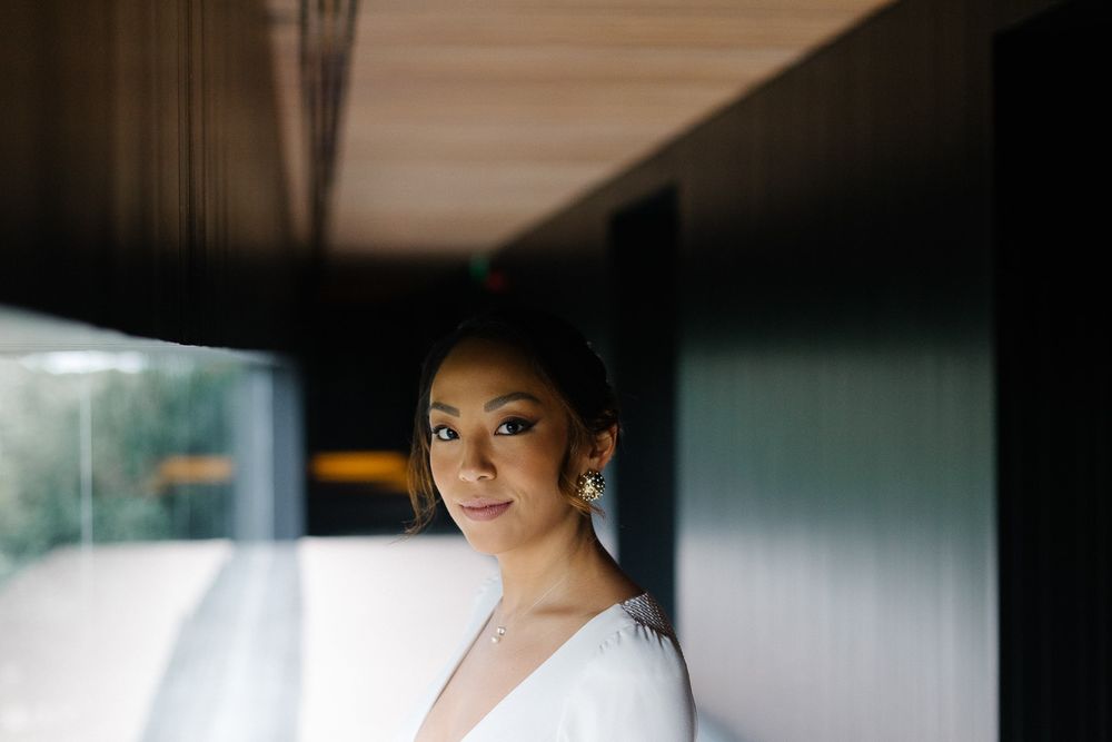 A bride stands elegantly in white against a modern interior backdrop.